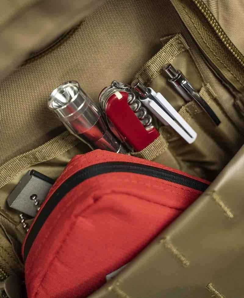 Mochila táctica beige con organizador interior y botellas en compartimento.