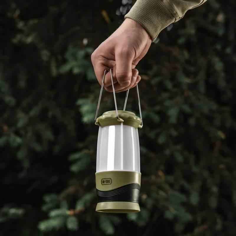 Linterna portátil encendida con cuerpo blanco traslúcido y asa plegable metálica