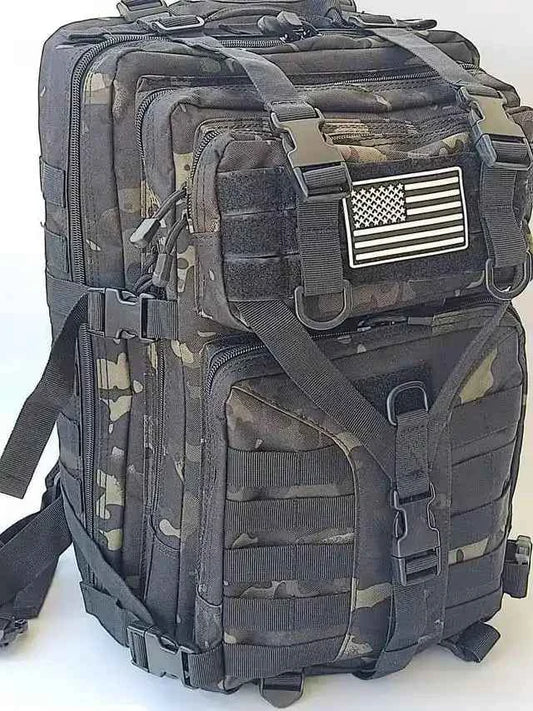 Mochila táctica camuflada con parche de bandera y bolsillos frontales con cremalleras.